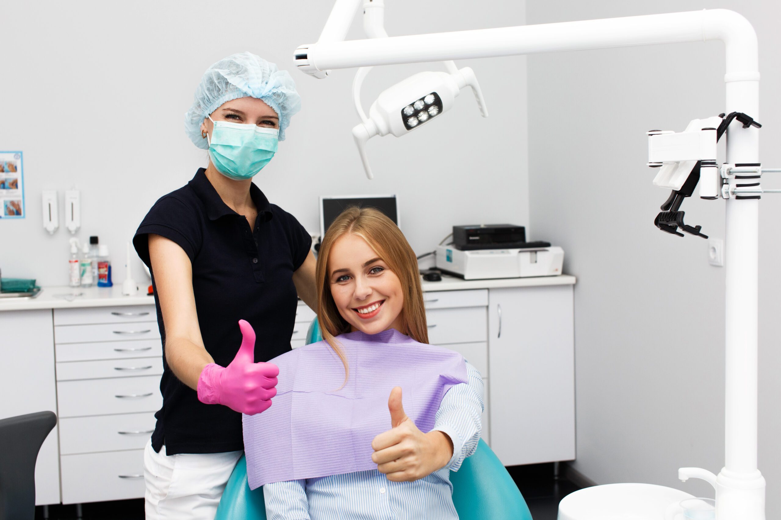 woman shows thumb up sitting with stomatologist dentist office scaled